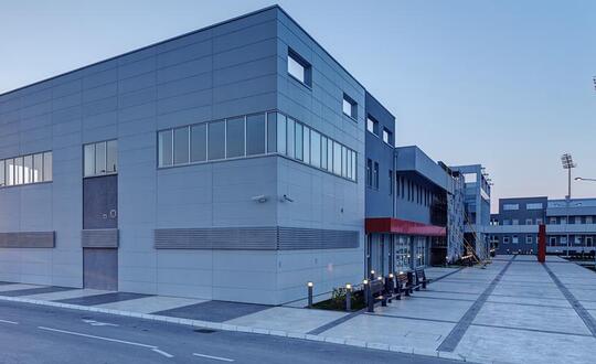 Modern industrial warehouse complex with articulated lorry bays and expansive paved area under clear sky at dusk.