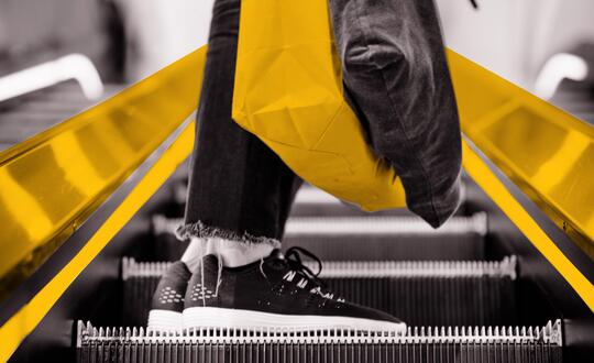 Person travelling up escalator with bags