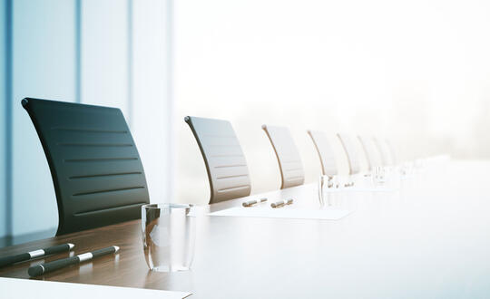 Chairs are lined up at a corporate business table for a meeting space.