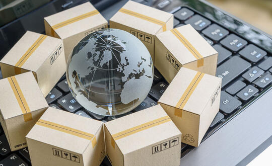 Small boxes are circled around a small globe, all positioned on top of a laptop keyboard.