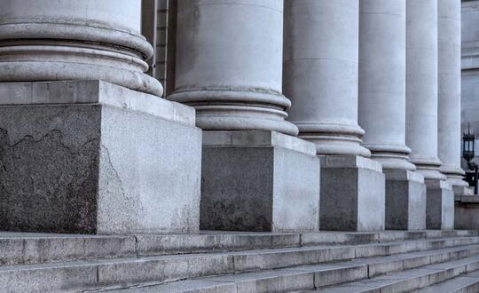 Columns of a classical architecture building with stone pillars, showing symmetrical design, with a view of the building's facade and elegant stonework, possibly a historic institution or courthouse in Britain.