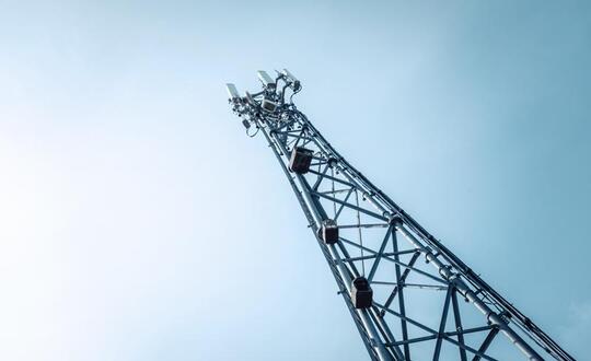 Low-angle view of a mobile phone mast against a clear sky, showcasing telecommunications infrastructure for wireless communication in the UK