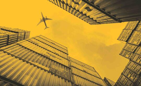 Plane flying over shipping containers