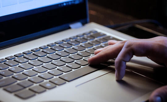 Detail of a man typing on a laptop. 