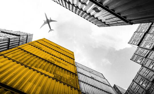 Upwards shot of plane flying over shipping cargo