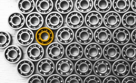 Image of black and white metal bearings with one highlighted in yellow