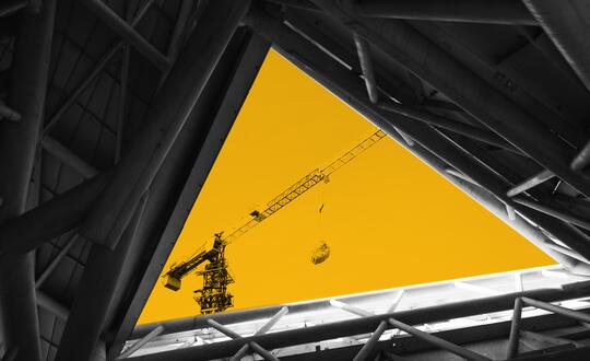 Crane framed by roof of modern building