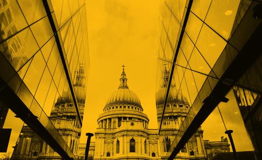 Shot of St Pauls' Cathedral framed by modern office buildings. Photo edited with a yellow wash.