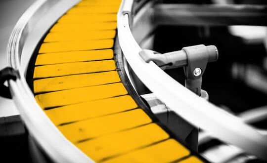 Close up of conveyor belt in manufacturing line. The belt is edited with a yellow wash.