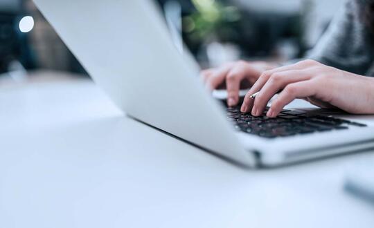 Detail of person typing on laptop.