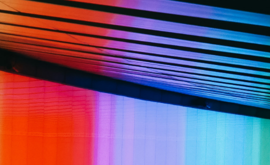 Colourful geometric light patterns on blinds with a vibrant rainbow gradient effect, showcasing modern interior design and contemporary lighting style.