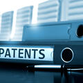 A binder labeled with "Patents" laying on a corporate meeting table - Shutterstock 504559510